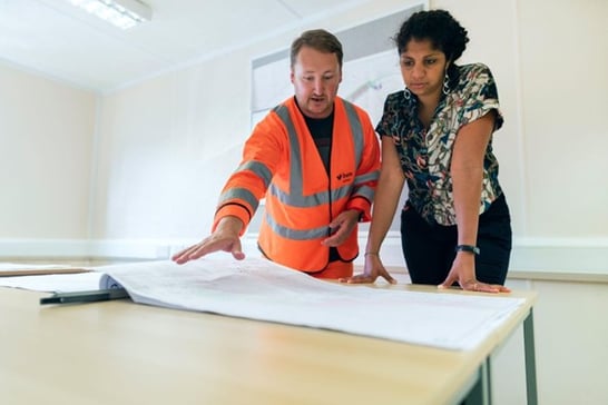 A construction estimator and engineer examine a plan
