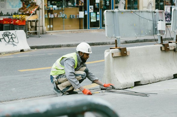 A construction worker wearing a hardhat and working on a road
