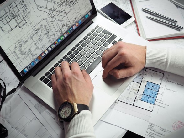 A construction professional analyzing a blueprint on a laptop