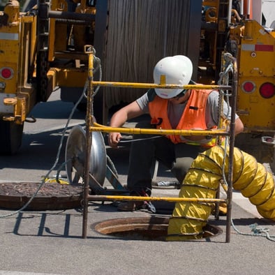 utility worker on site over manhole