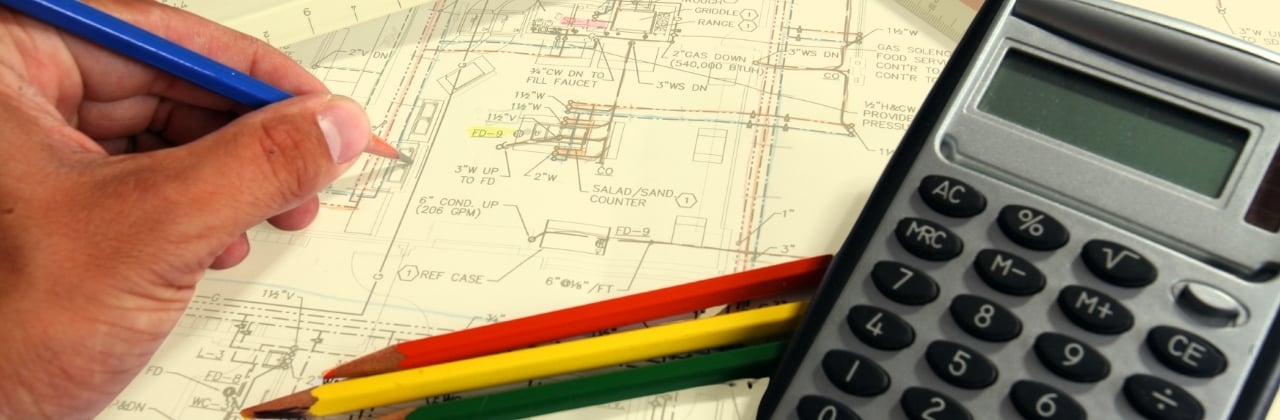 construction blueprint with pencils and calculator sitting on top